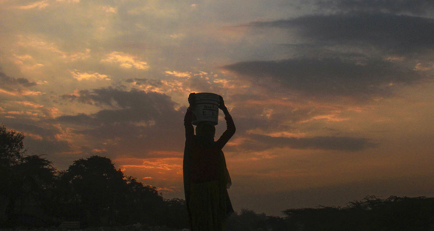 A woman silhouetted against scattered clouds walks during sunrise, in Gurugram, Haryana, on Thursday. 