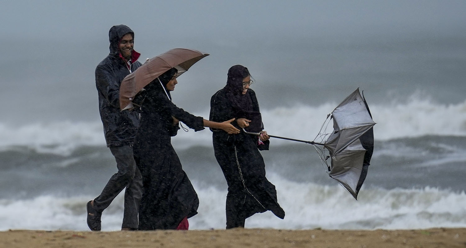 People look at the rough sea amid rainfall due to Cyclone Ditwah at Marina Beach, in Chennai, on Monday.